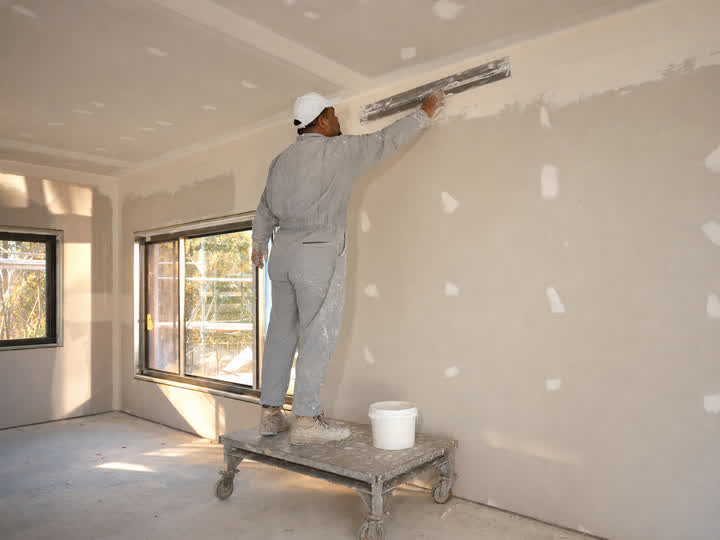 A plasterer trowelling a joint on a new gyprock wall